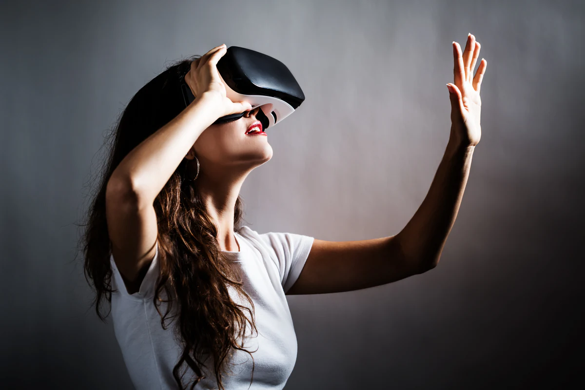 Woman in a VR headset reaching out to touch a virtual object