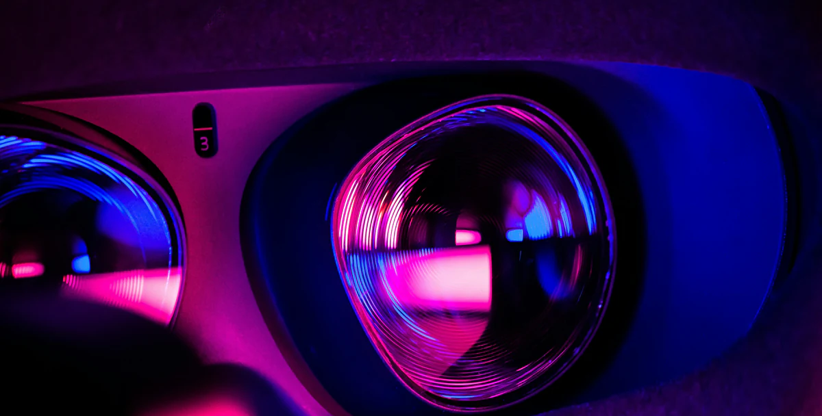Close-up of a VR headset's lenses lit in pink and blue